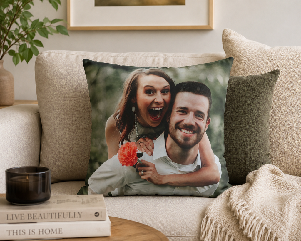 Decorative pillow with a couple's photo on a couch with books and a candle.