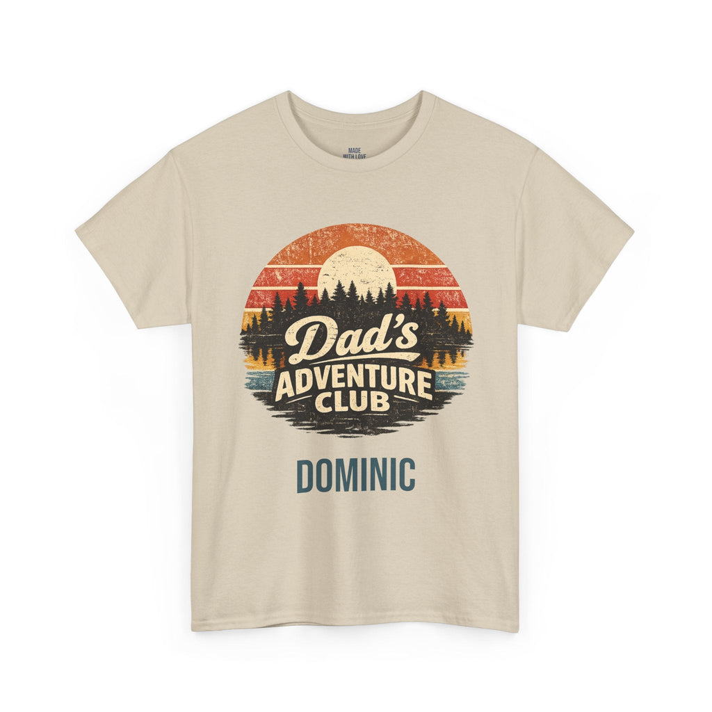 A beige crewneck t-shirt featuring a retro circular graphic with a sunset landscape and the text 'Dad's Adventure Club' above the name 'DOMINIC' printed in blue.