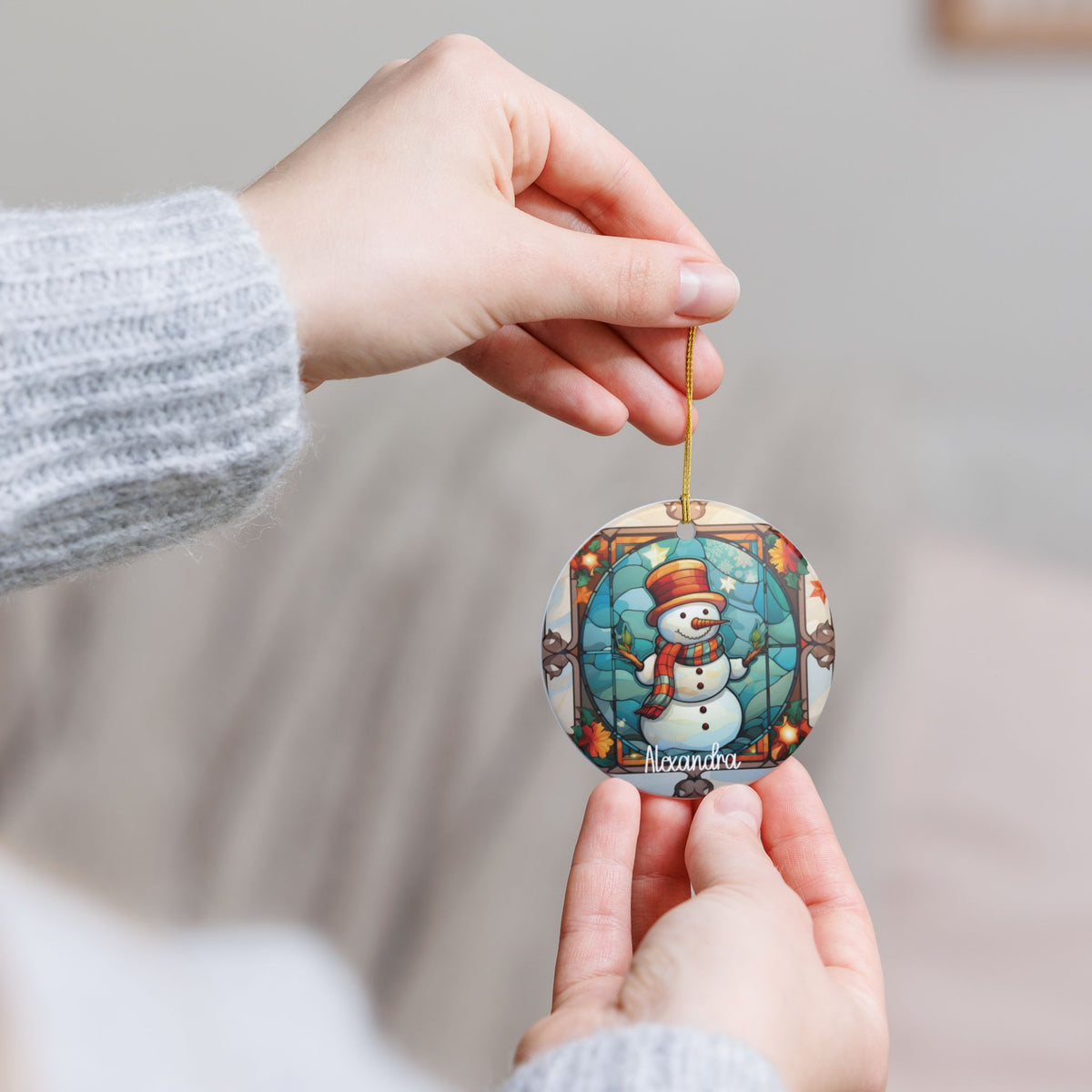 Hand holding the personalized Autumn Stained Glass Snowman ornament by its gold string