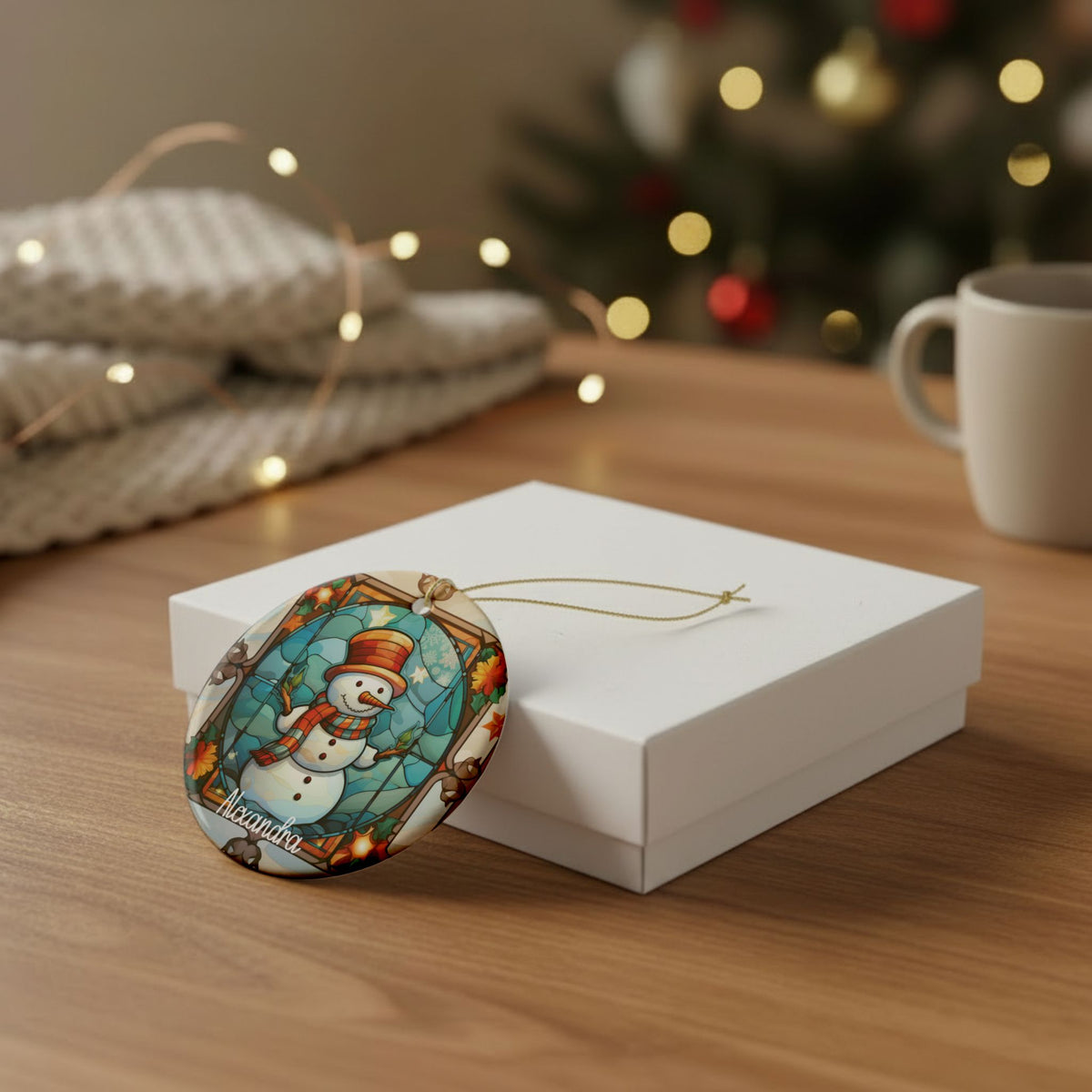 Autumn Stained Glass Snowman ornament leaning against a white gift box on a wooden table