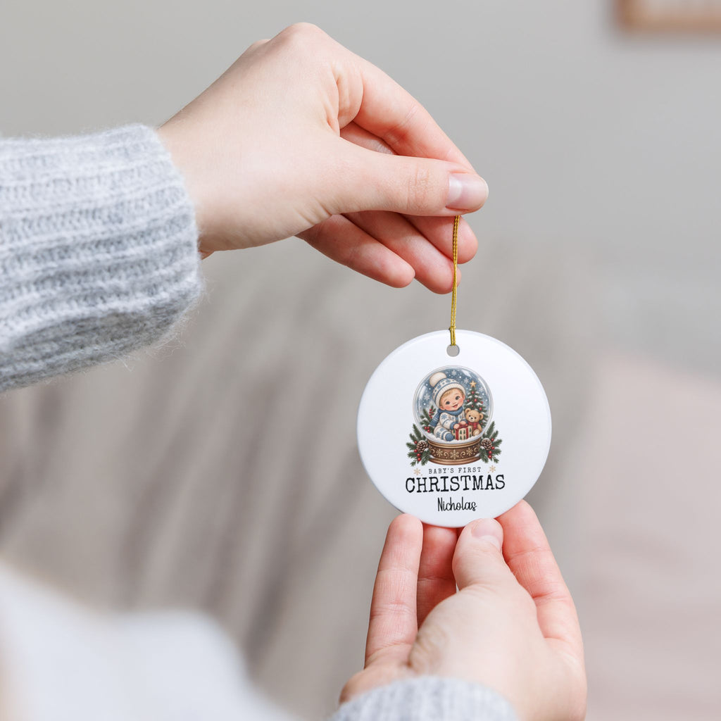 Hand holding the personalized Baby's First Christmas Snow Globe ornament by its gold string