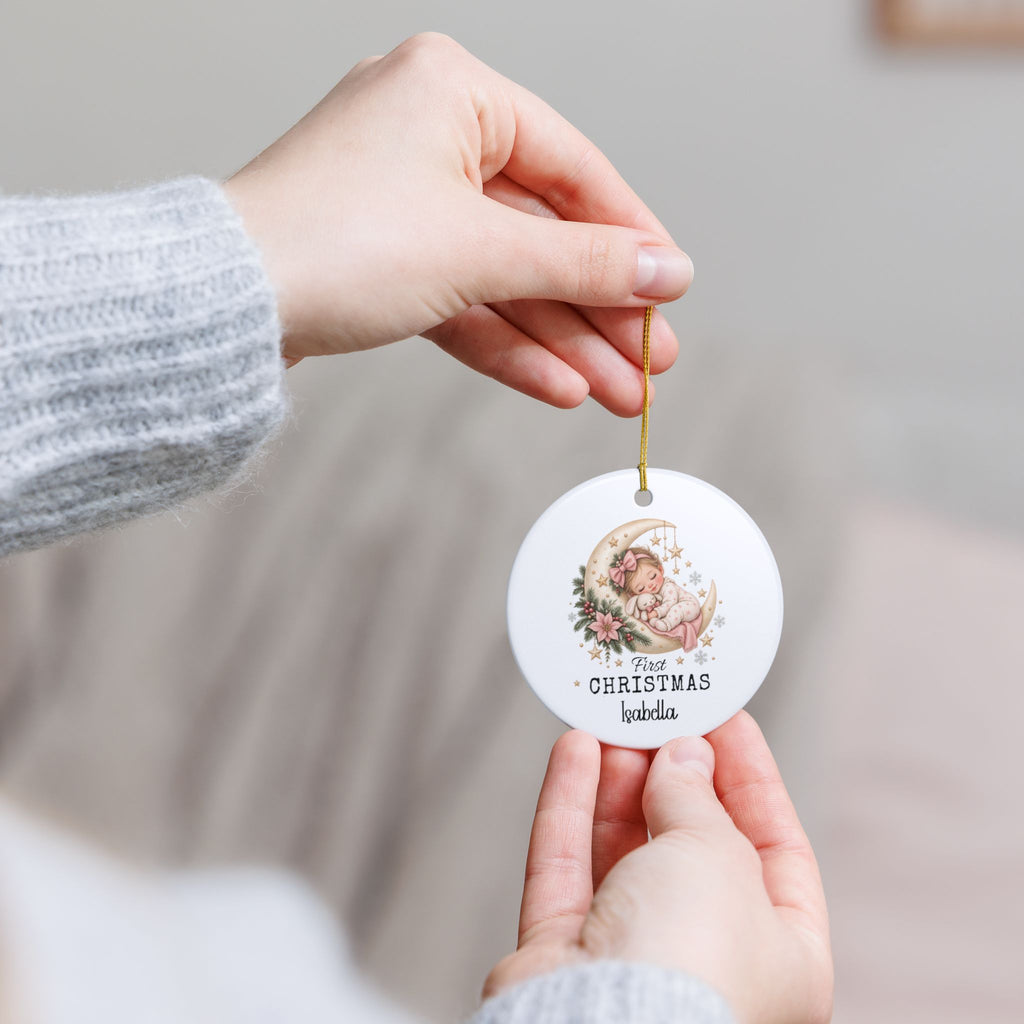 Hand holding the personalized Baby Girl First Christmas Moon ornament by its gold string