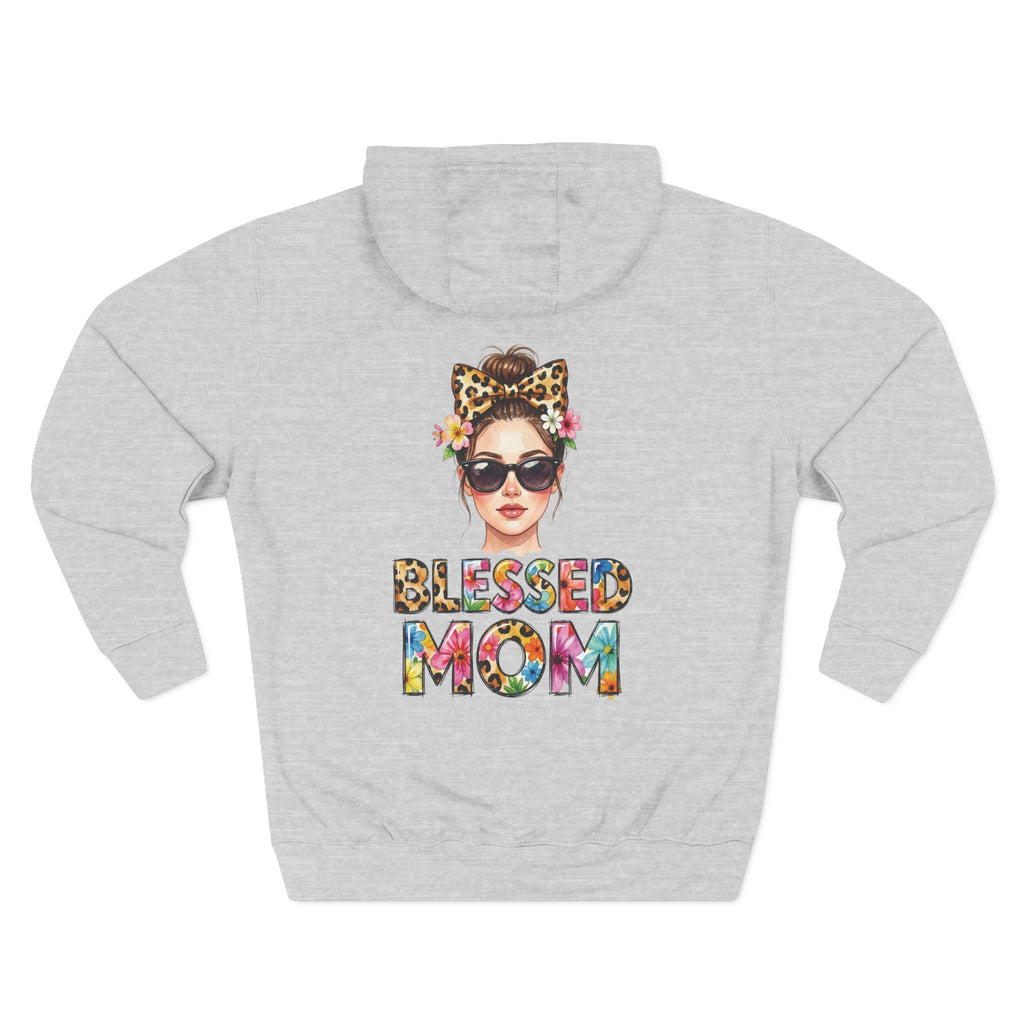 A light heather gray hoodie shown from the back, featuring a colorful graphic of a woman with sunglasses, a leopard-print bow headband, and flowers, with the text 'BLESSED MOM' in a multicolor tie-dye pattern below. For mom.