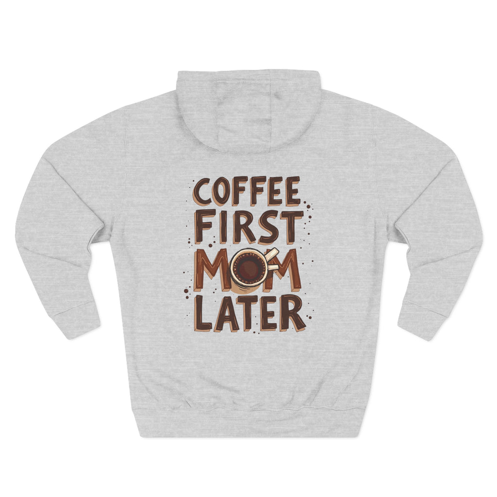 A heather grey long-sleeve hoodie shown from the back, featuring a graphic print that reads 'COFFEE FIRST MOM LATER' in brown lettering with a coffee cup illustration. Special gift for mom.