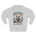 A light heather gray hoodie shown from the back, featuring a graphic of a raccoon with the text 'MOM BRAIN: PLEASE HOLD' and 'Groak Nature Vibe' in green, orange, and dark gray lettering. For mom.