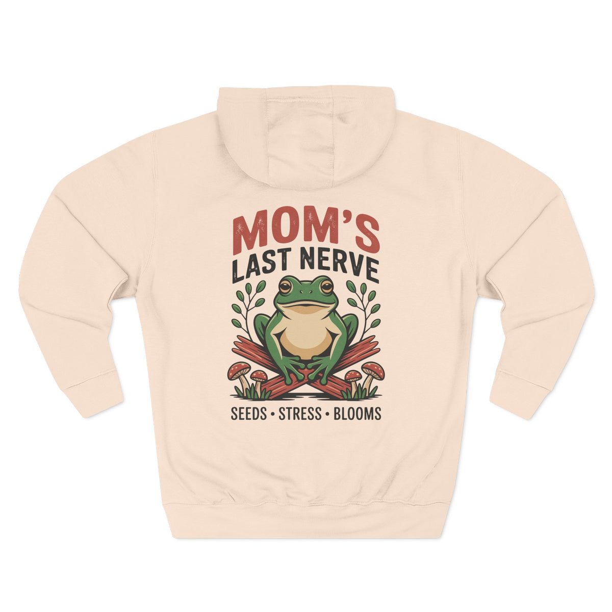 A pale pink hoodie shown from the back, for Mom. featuring a graphic print of a green frog sitting on crossed red mushrooms with the text 'MOM'S LAST NERVE' and 'SEEDS - STRESS - BLOOMS'. 