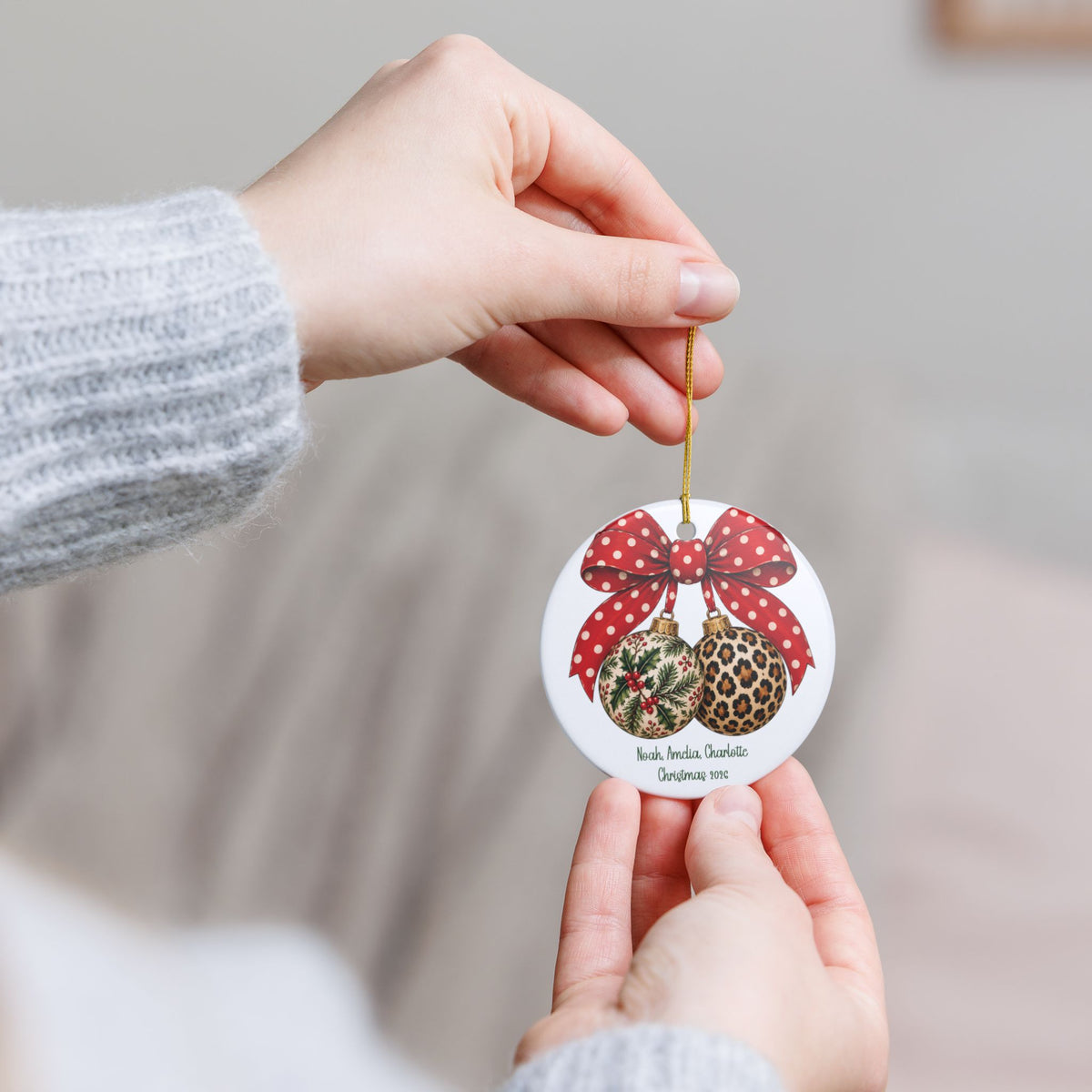 Hand holding the personalized Christmas Bow & Baubles ornament by its gold string