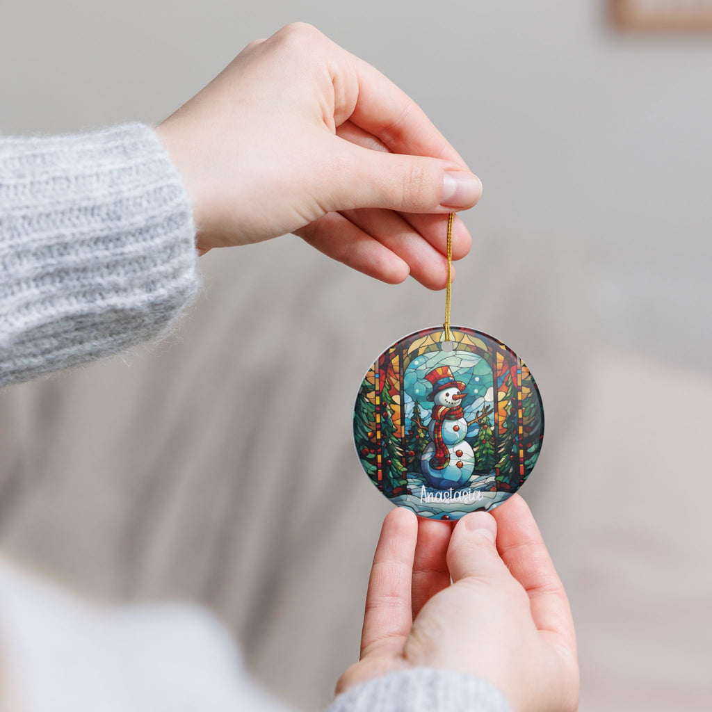 Hand holding the personalized Christmas Forest Stained Glass Snowman ornament by its gold string