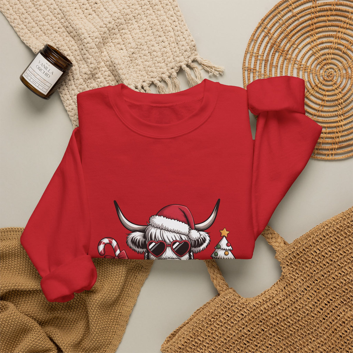 Red personalized Highland Cow Christmas sweatshirt, flat lay with cozy knit blanket