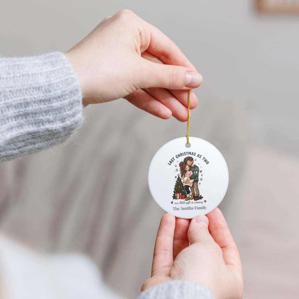 Hand holding the personalized Last Christmas as Two ornament by its gold string