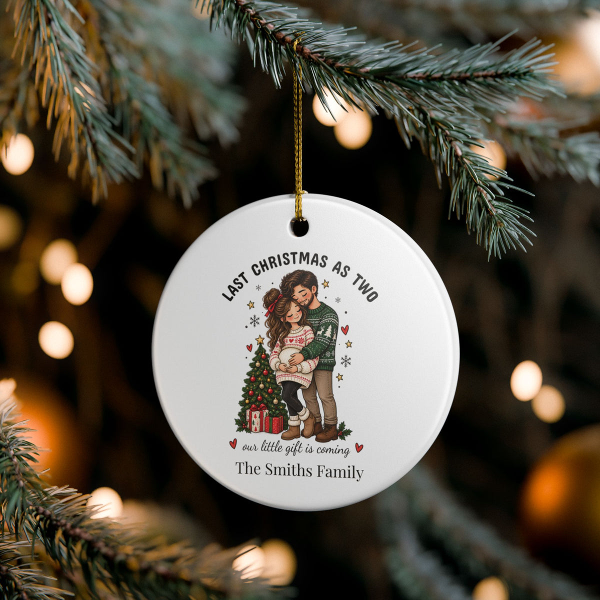 Personalized pregnancy announcement ornament hanging on a pine branch with soft bokeh lights