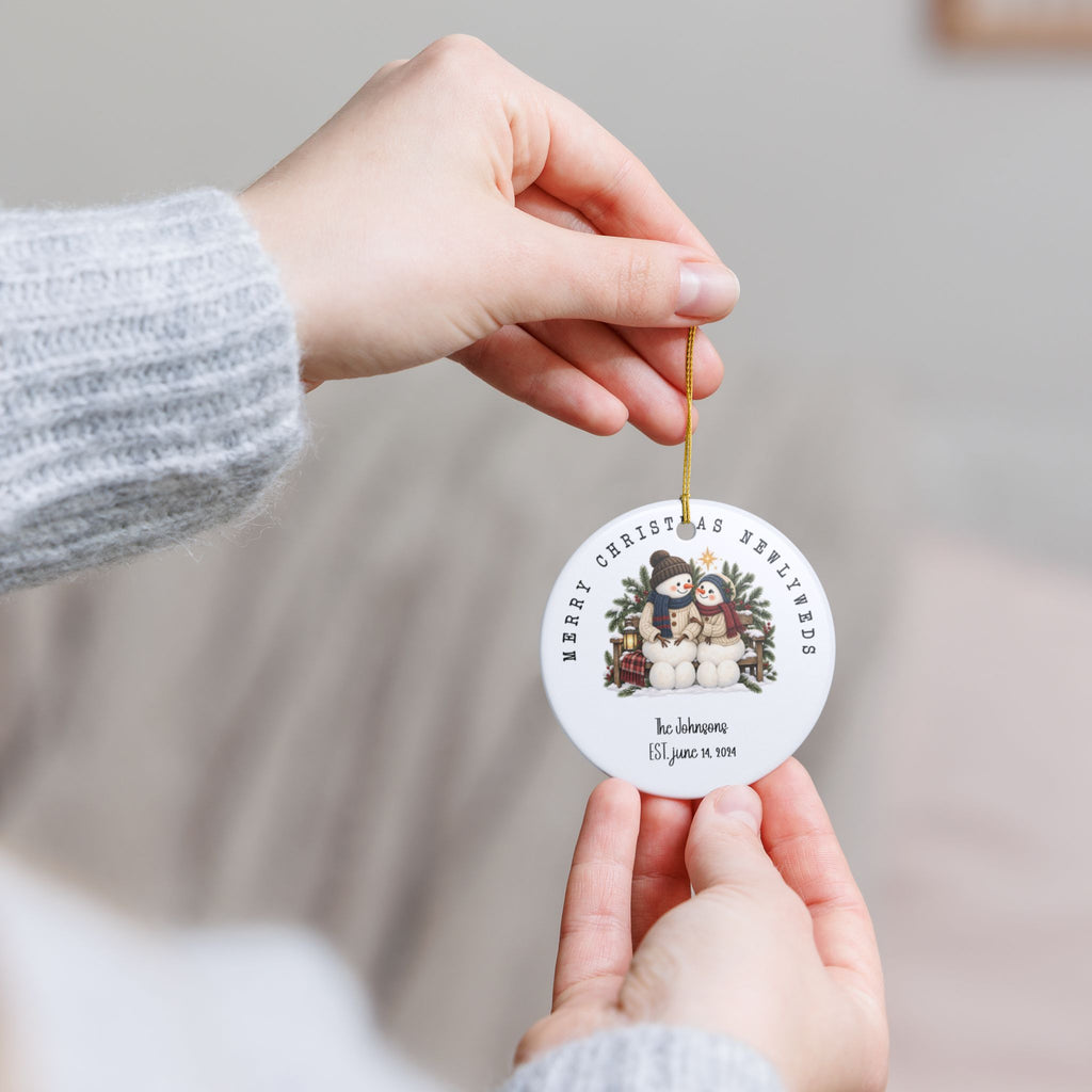 Hand holding the personalized Merry Christmas Newlyweds ornament by its gold string