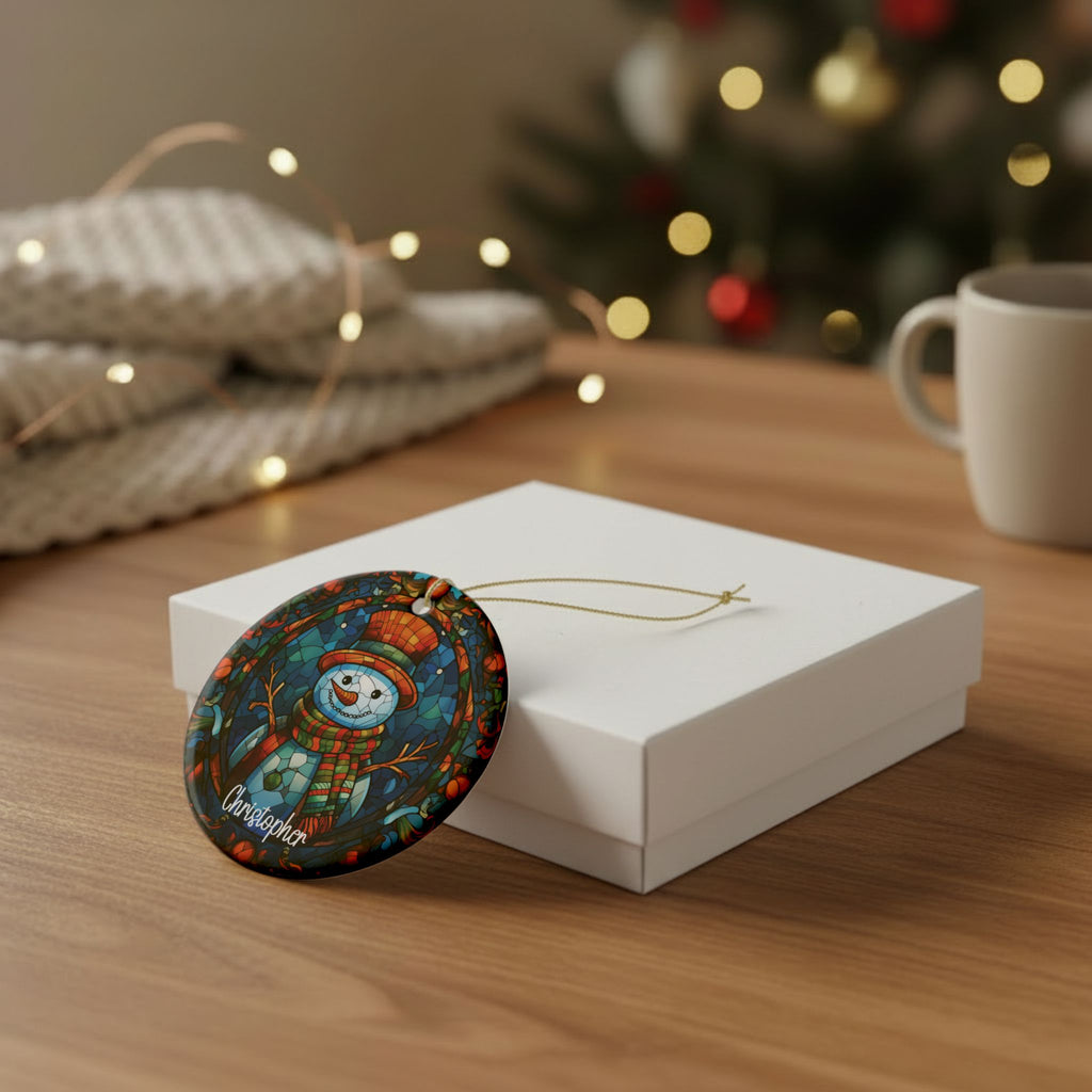 Colorful Mosaic Snowman ornament leaning against a white gift box on a wooden table