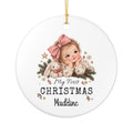 Personalized My First Christmas Baby Girl ornament with a baby girl in a pink bow, a white bunny and Christmas greenery, front view