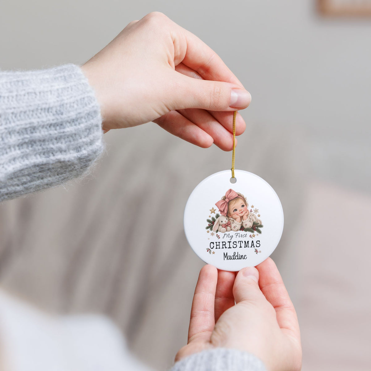 Hands holding the personalized My First Christmas Baby Girl ornament to show its size