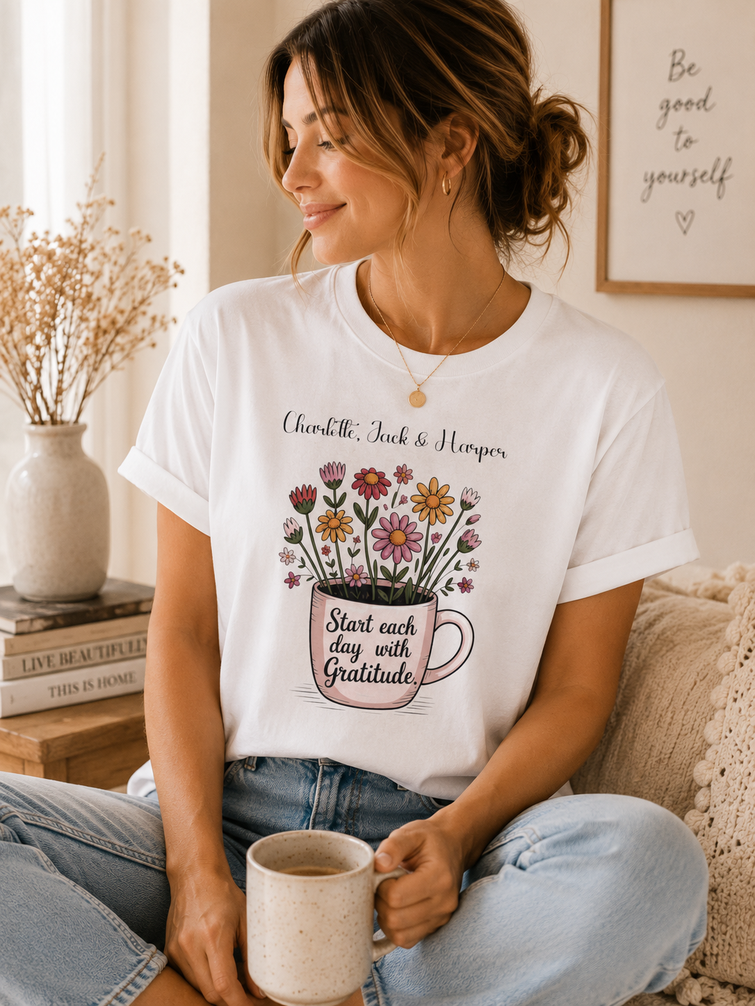 Woman wearing a personalized white gratitude T-shirt with floral mug design and custom children’s names, holding a coffee mug at home.