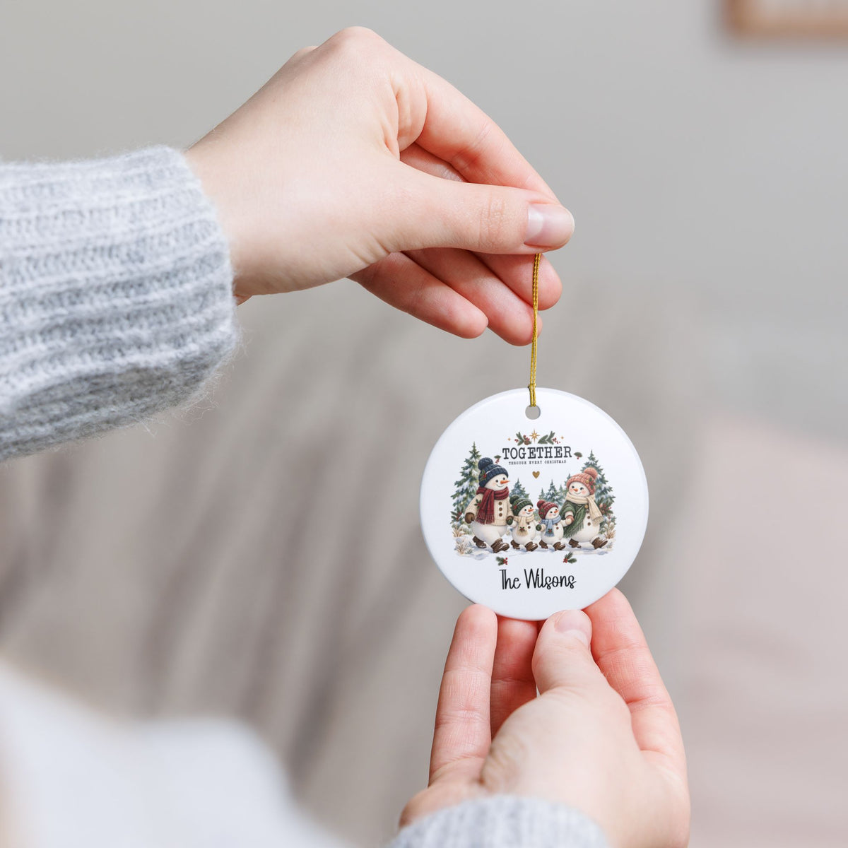 Hand holding the personalized Together Through Every Christmas ornament by its gold string