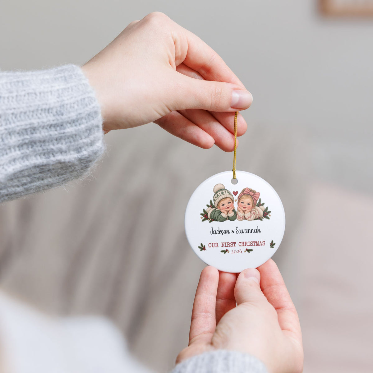Hand holding the personalized Twins First Christmas ornament by its gold string