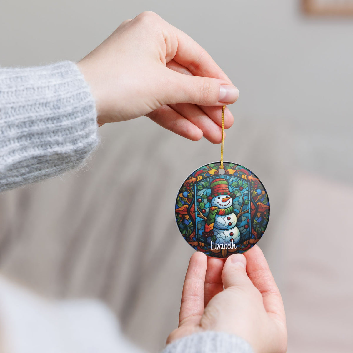Hand holding the personalized Woodland Stained Glass Snowman ornament by its gold string